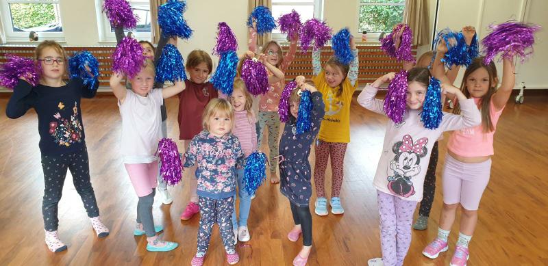 Kinder mit bunten Pompons beim Tanzen