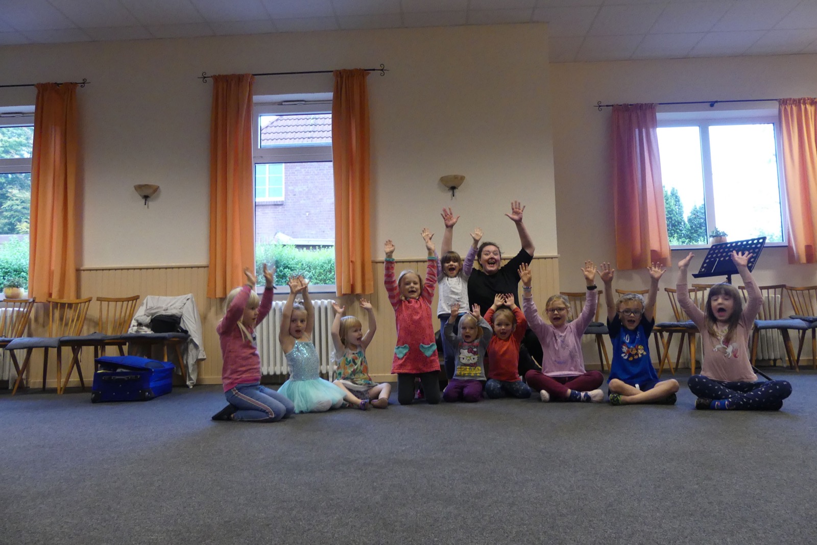 Eine Kindergruppe sitzt mit erhobenen Armen im Kreis